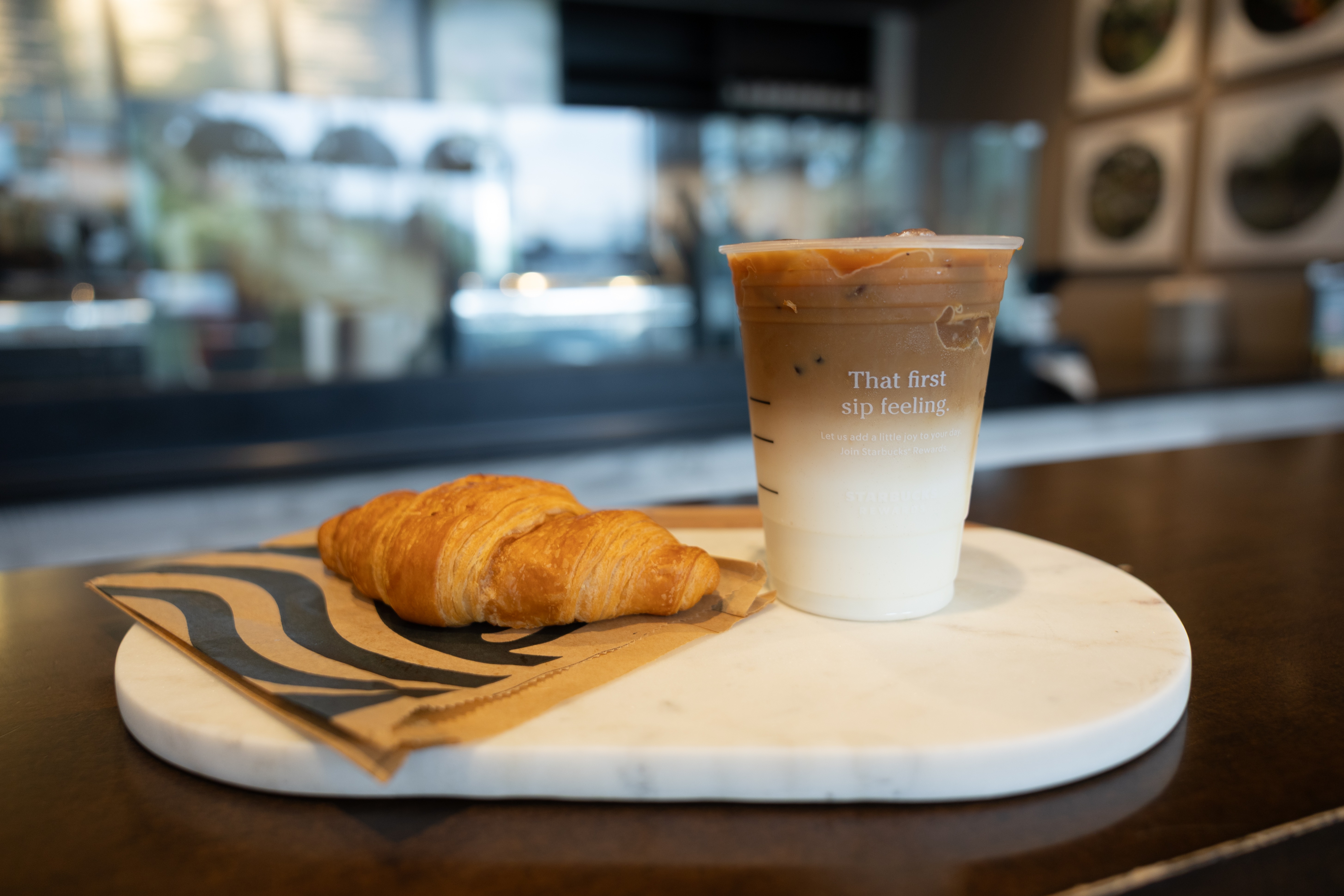 A Starbucks Combo including a drink and croissant sits on the Starbucks counter