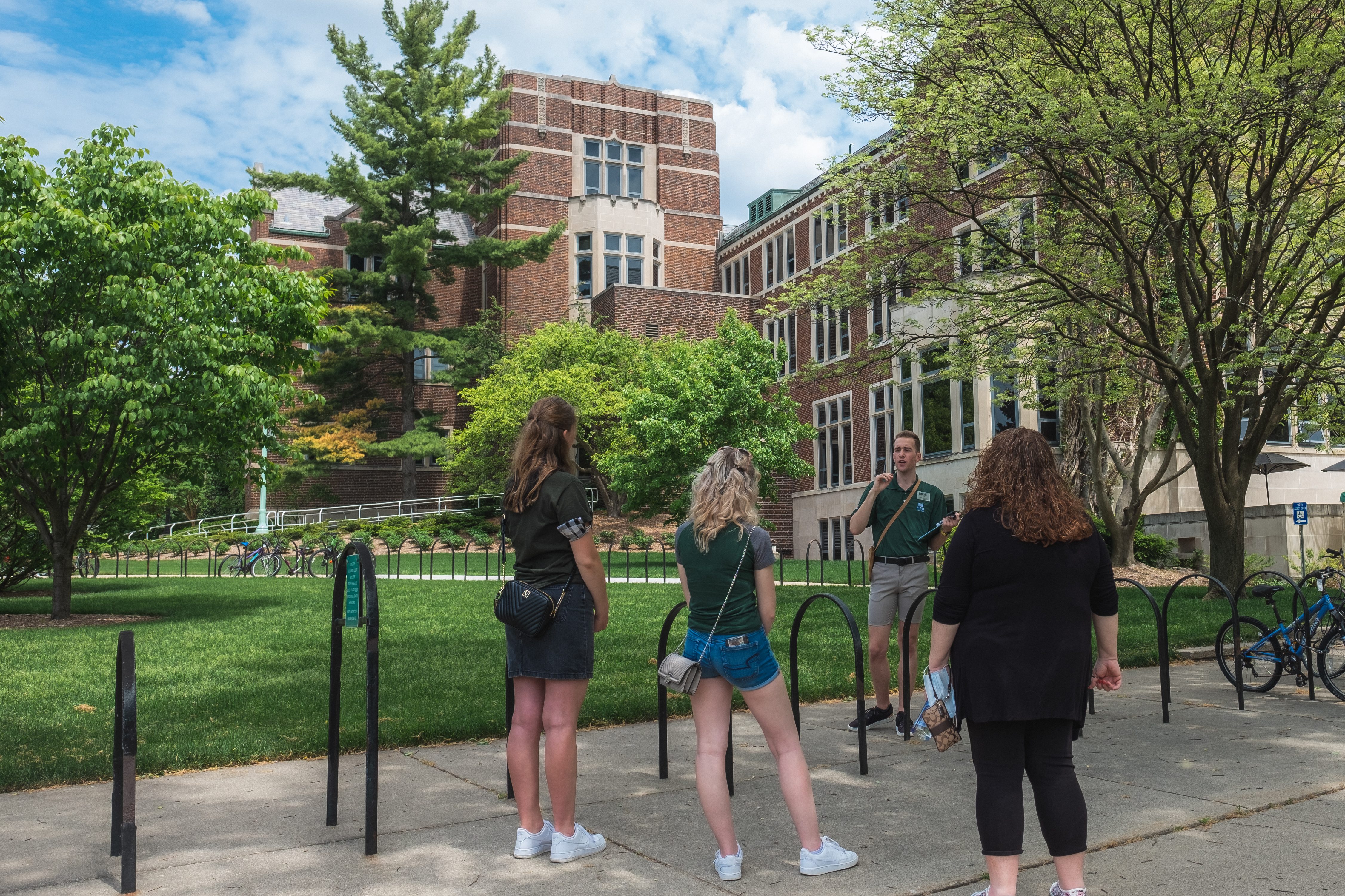 An MSU tour guide speaks to a small group on MSU's campus during a warm, sunny day