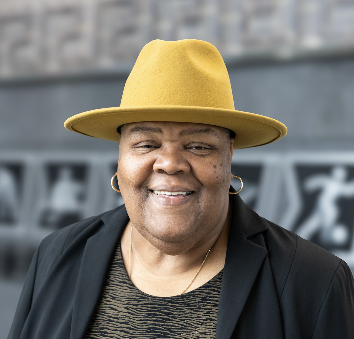 A headshot of Culinary Services’ Brenda Nelson on campus wearing a hat and blazer.