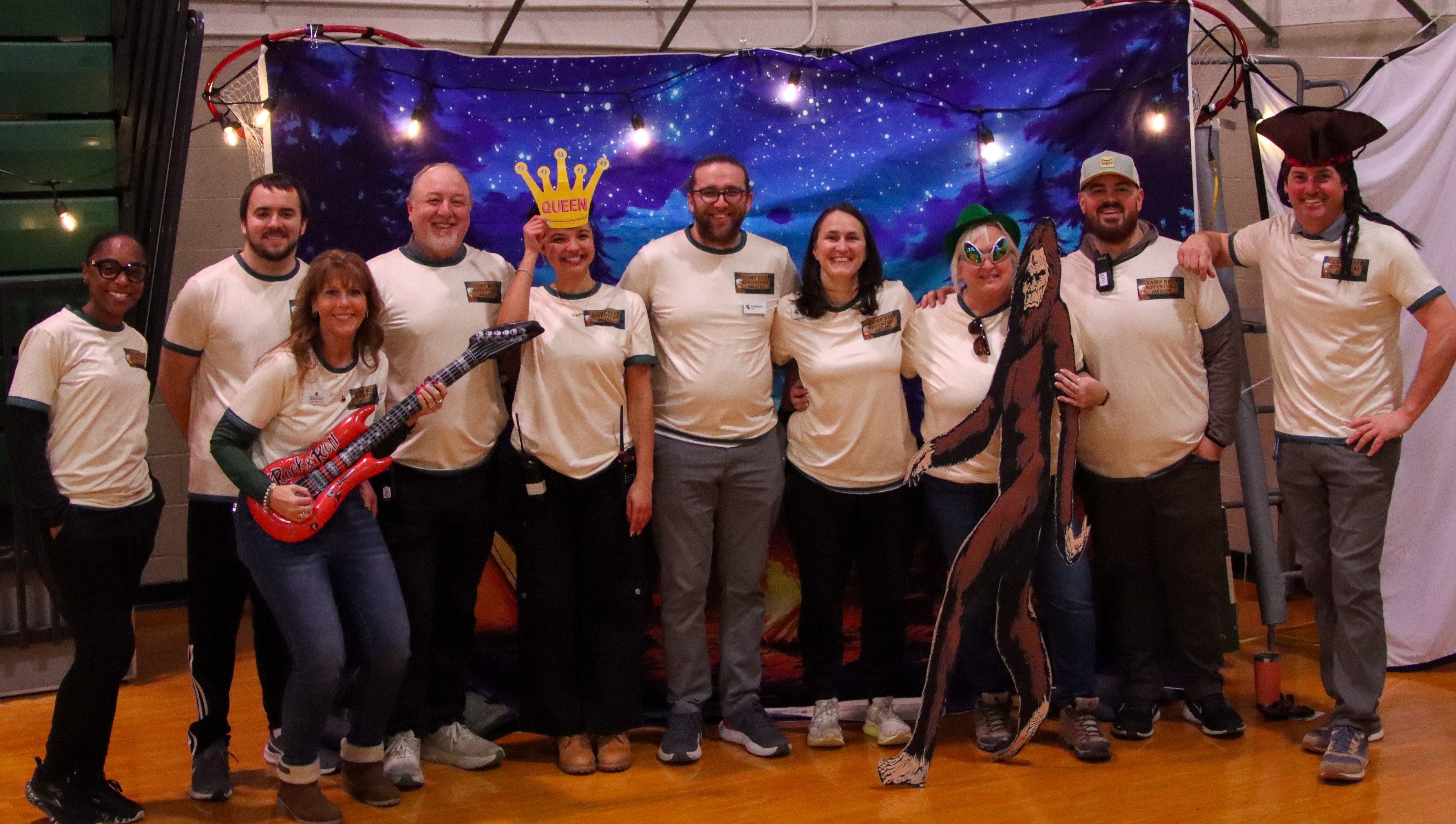 A group of MSU Rec Fest administrative staff pose together in front of a backdrop depicting a night sky