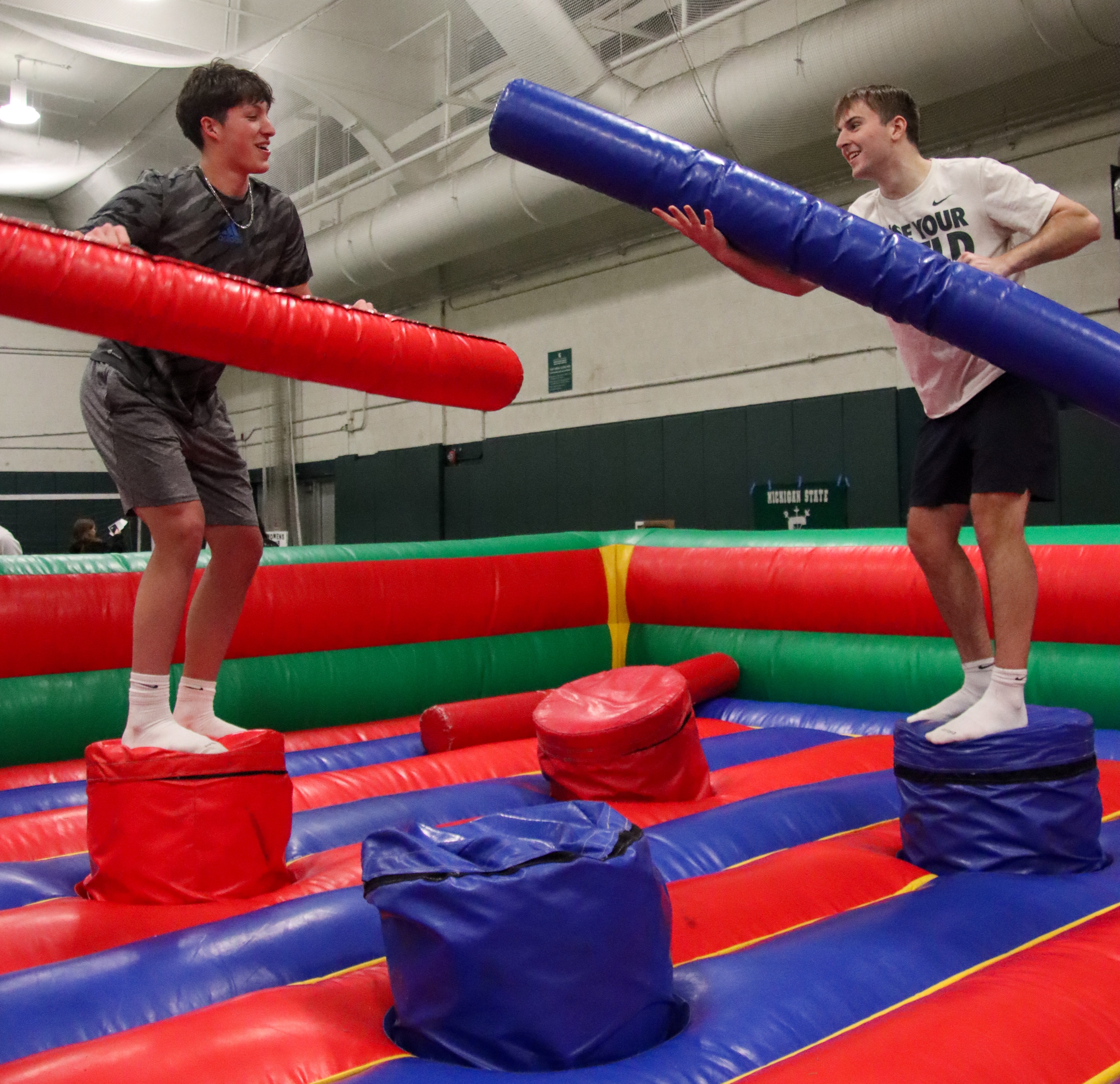 Two students joust using inflatable props at MSU's rec fest