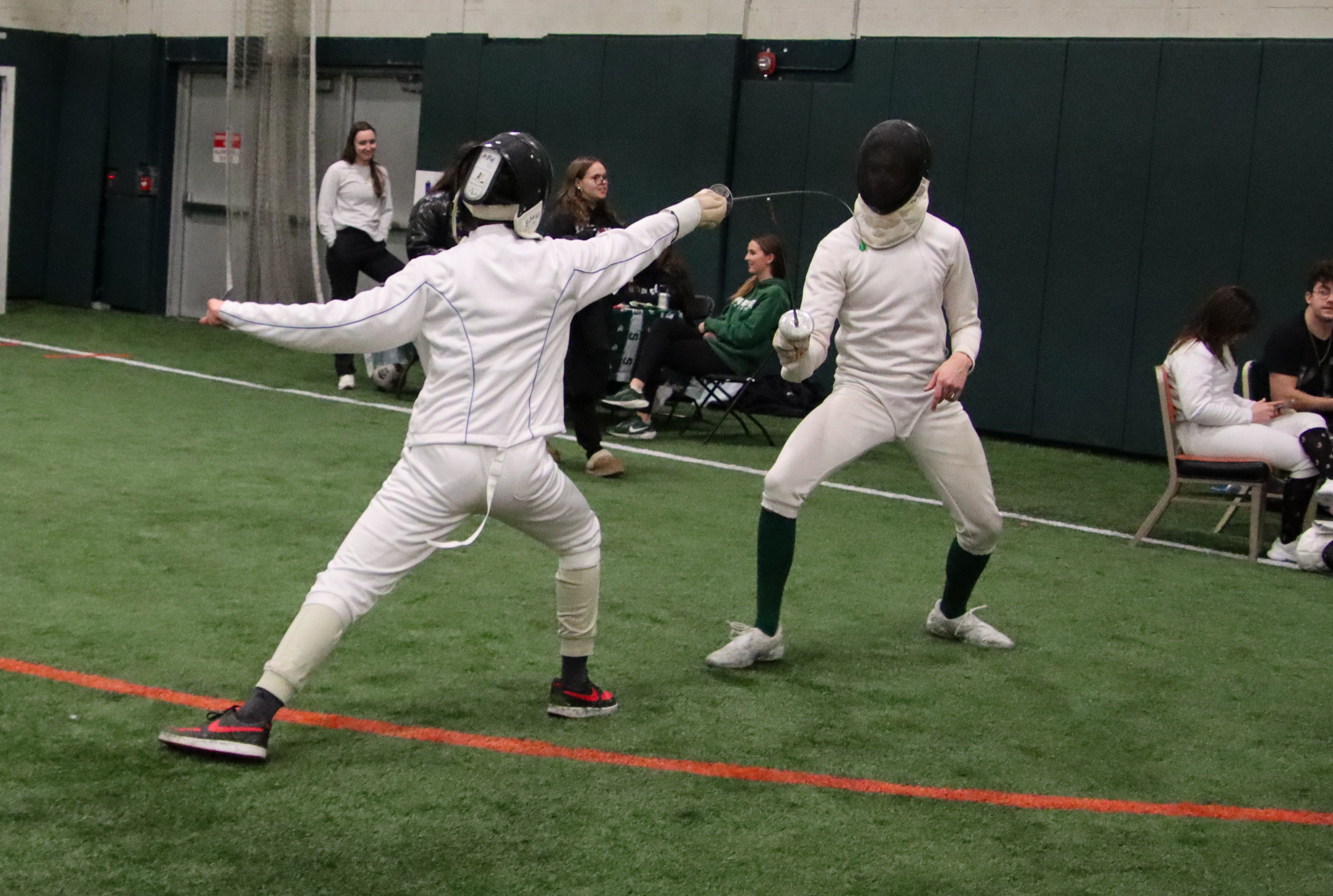 Two students in full fencing attire demonstrate the art of fencing