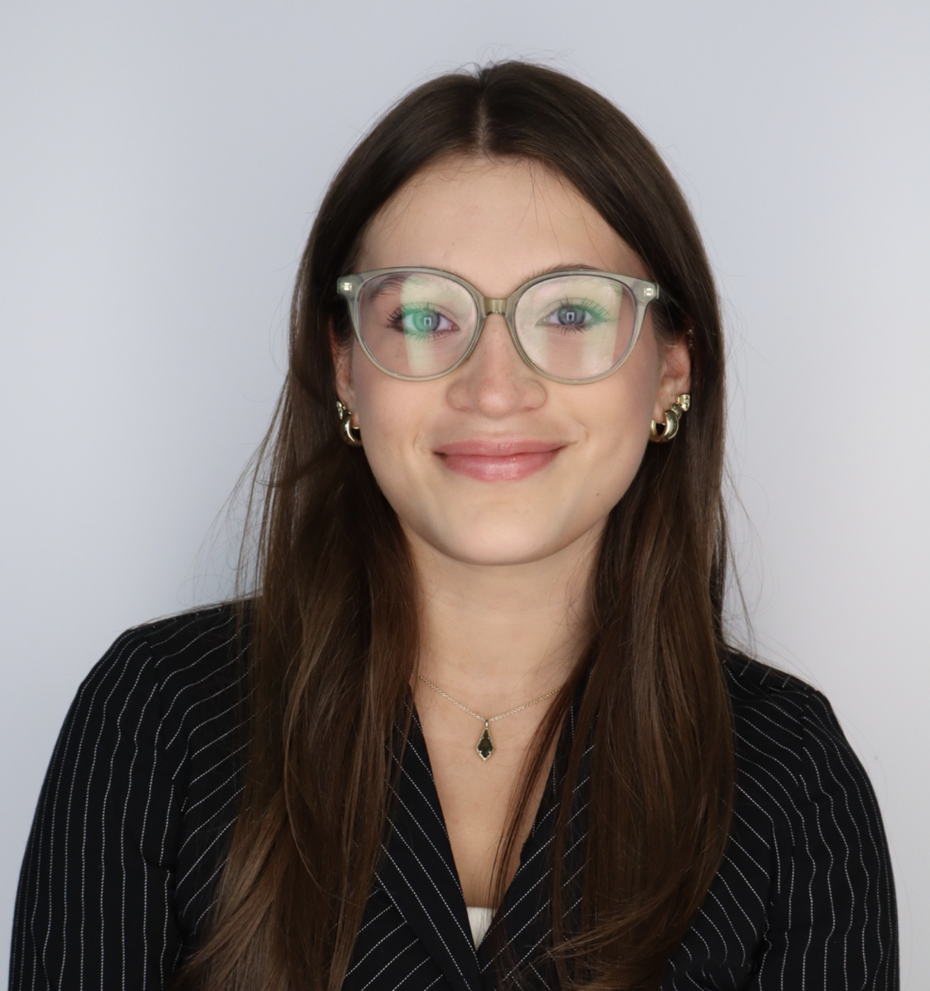 RCU Scholarship Victoria Bucher poses for a professional headshot wearing glasses and striped blazer.