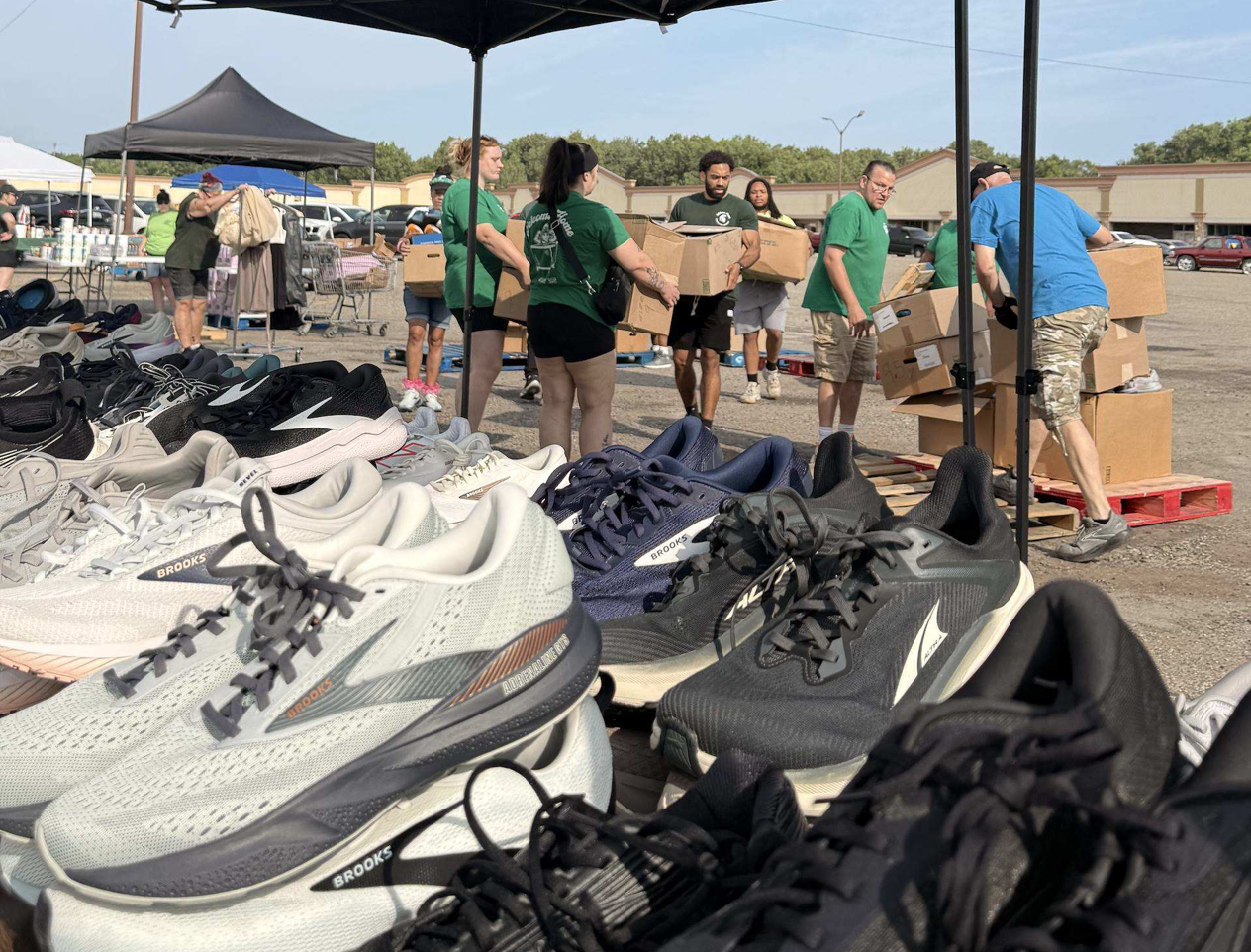 Team members carry boxes, staging materials distributed at Fresh Food Fridays, including tennis shoes and other clothing items.