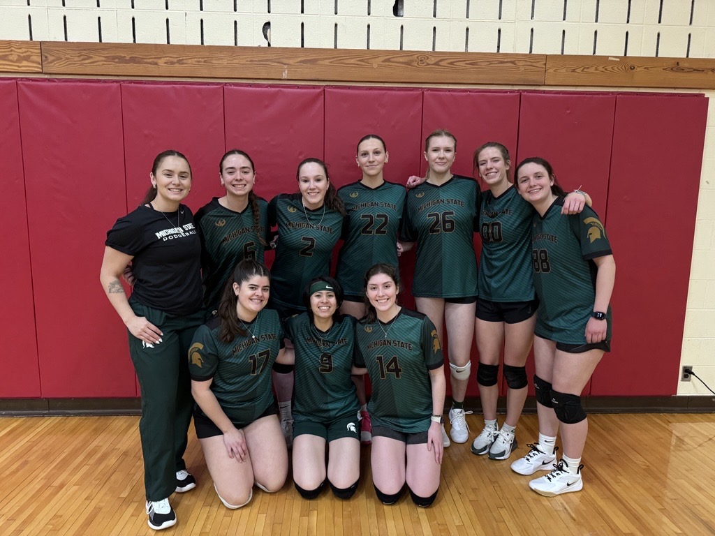 MSU Club Dodgeball team members pose in green Michigan State uniforms in from of a red mat
