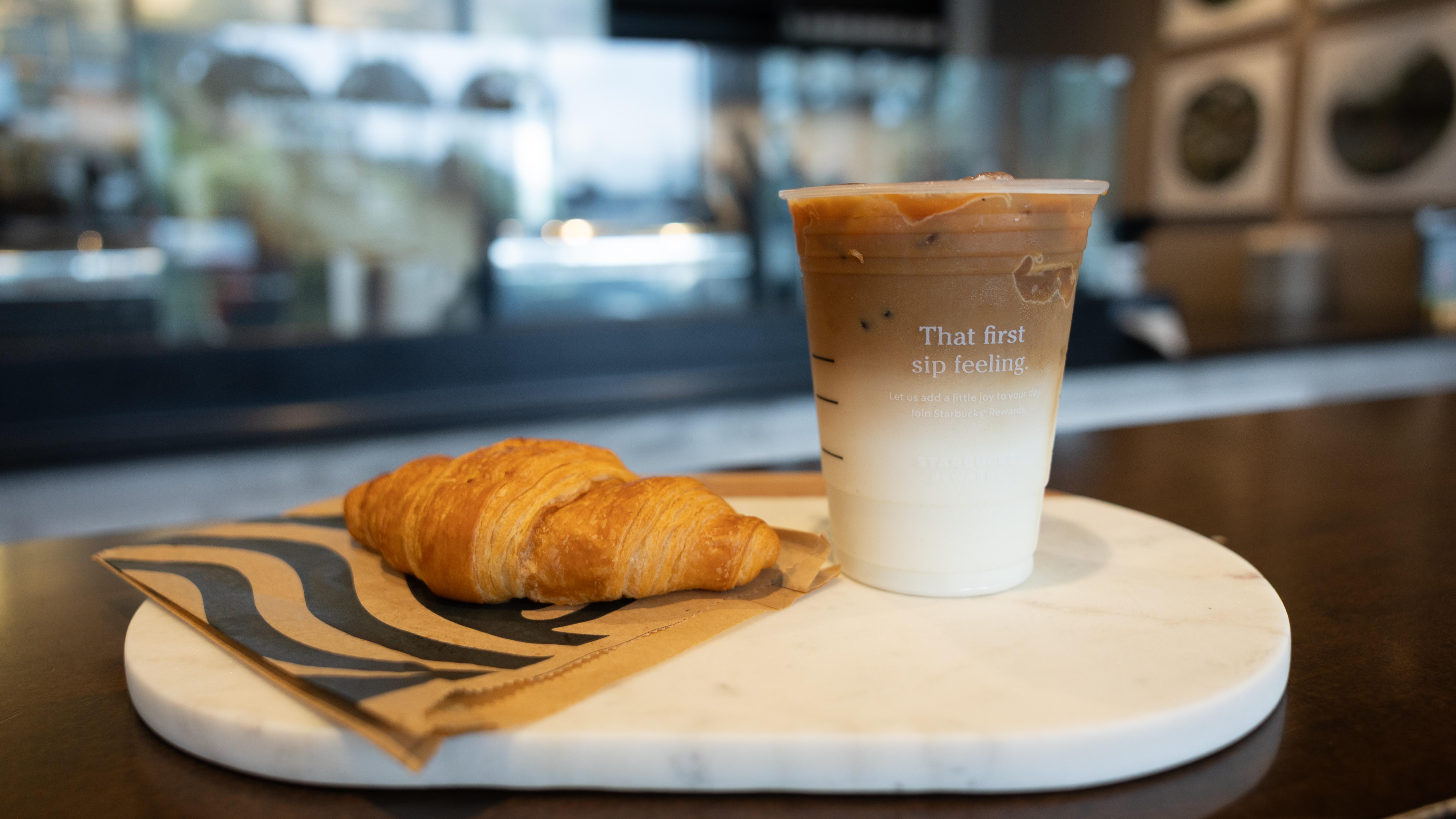 A Starbucks Combo including a drink and croissant sits on the Starbucks counter