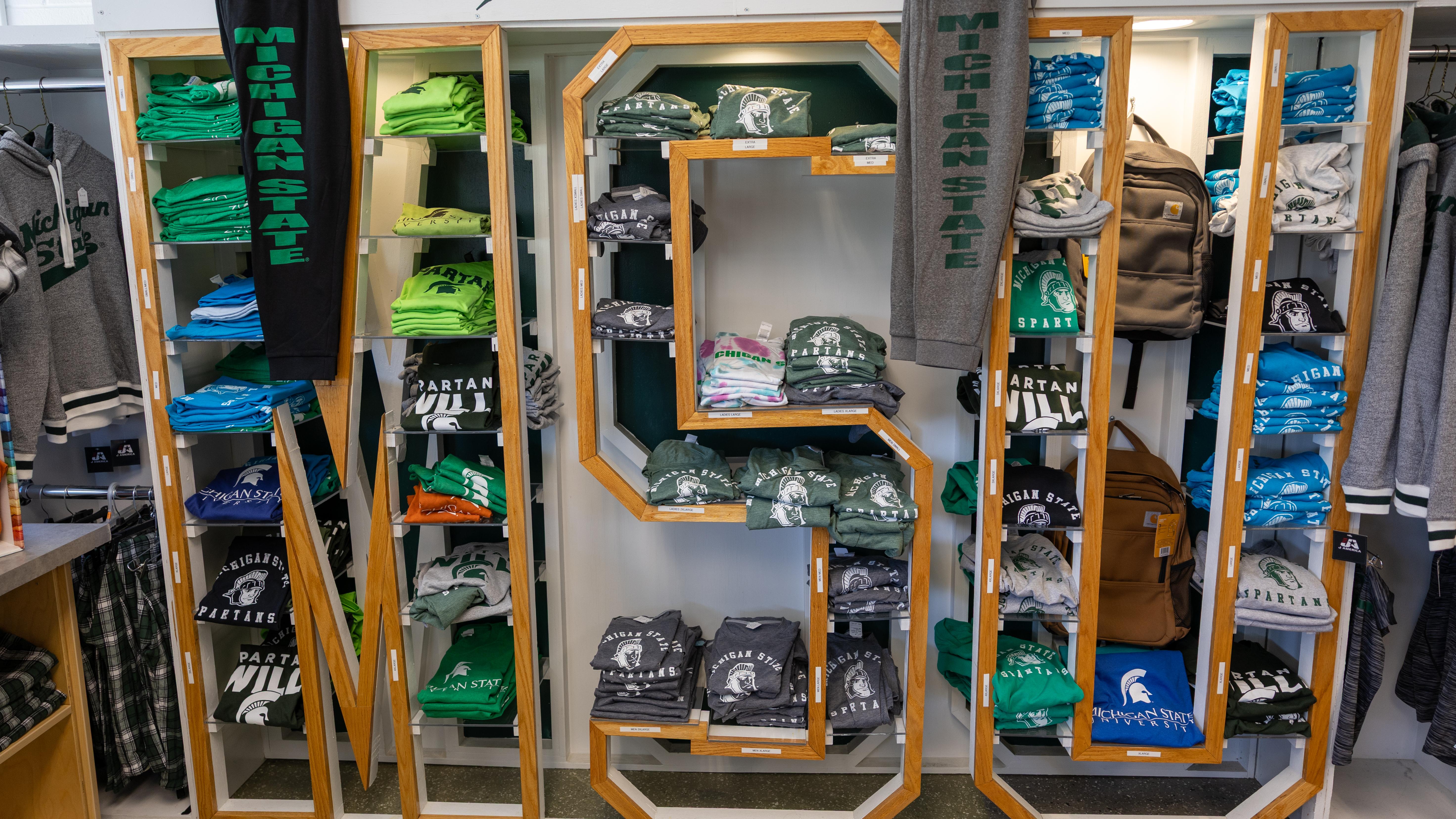 A display at Spartan Linen Services shows available clothing items stacked on shelving in the shape of the letters “MSU."