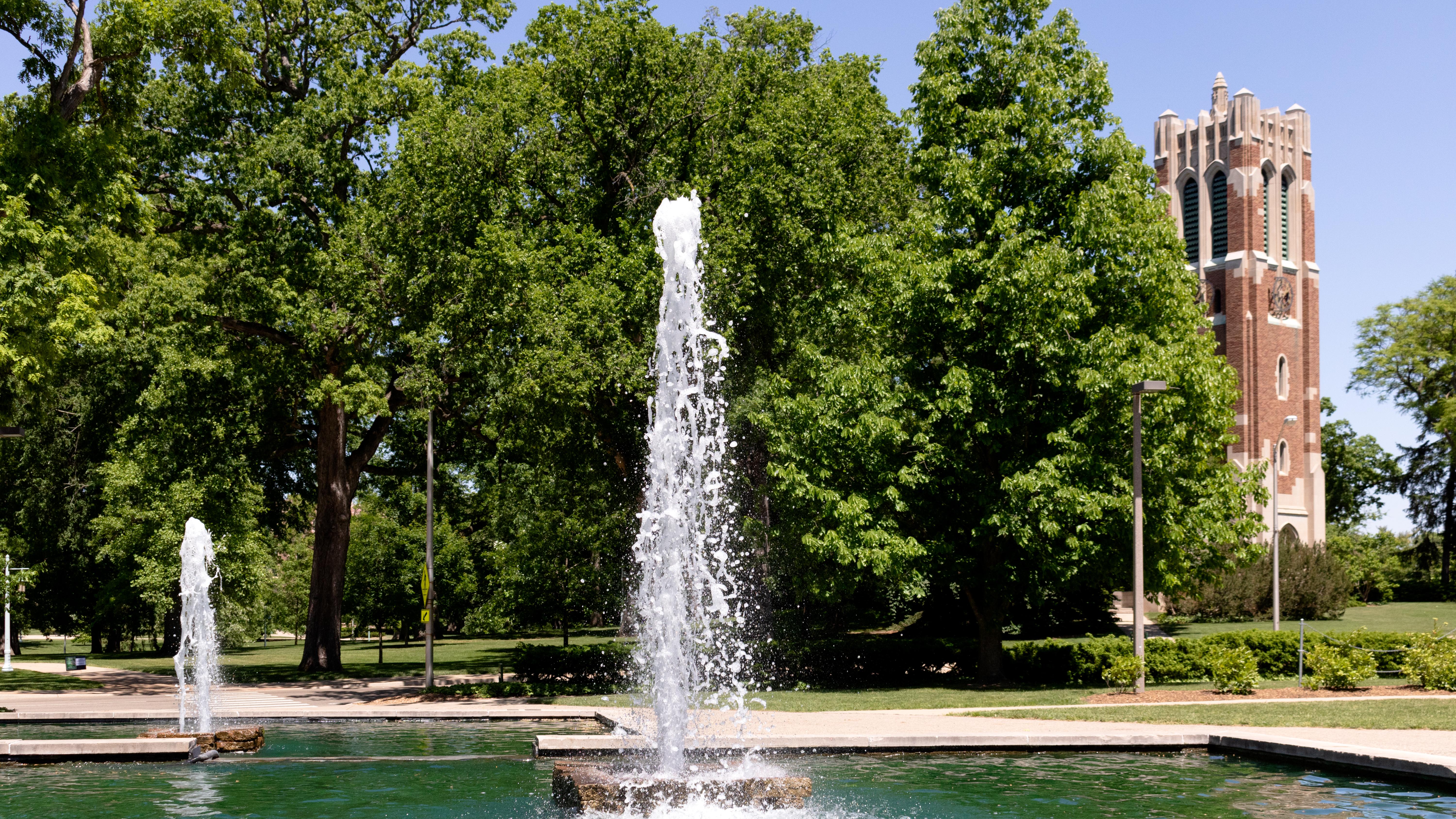 Image of the MSU Library fountains on a summer day with Beaumont Tower and trees in the background.